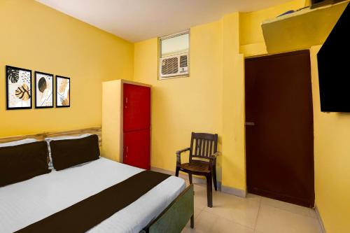1 dormitorio con cama, puerta roja y silla en Hotel O Egmore Metro Station Chennai Formerly Harini Lodge, en Chennai
