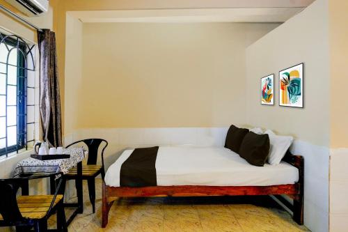 アランボールにあるHotel O Arambol Beach Formerly Hakuna Matataのベッドとテーブルと窓のある寝室