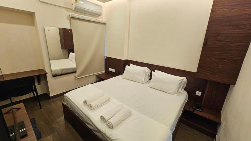 a bedroom with a bed with white sheets and a mirror at Chippy Inn Tharamani in Chennai