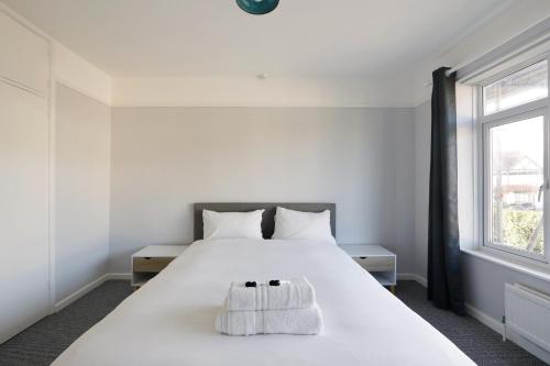a bedroom with a white bed and a window at Spacious 2-Bedroom Flat Near Rottingdean Beach & Windmill in Brighton & Hove