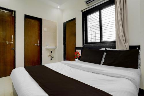 a bedroom with a large bed with a window at Hotel O Sai Teerth Theme Park Formerly Sai Dhanlaxmi in Shirdi