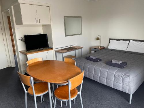a small room with a bed and a table and a television at Bella Tuscany Motor Lodge in Napier