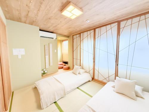 two beds in a room with windows at Ōimazato-Japanese Garden Japanese Entire House with T a t ami Rooms for 8 & 5 Minutes Walk to Imazato &2 Baths 2 Toilets &Direct to Namba and Nipponbashi in Osaka