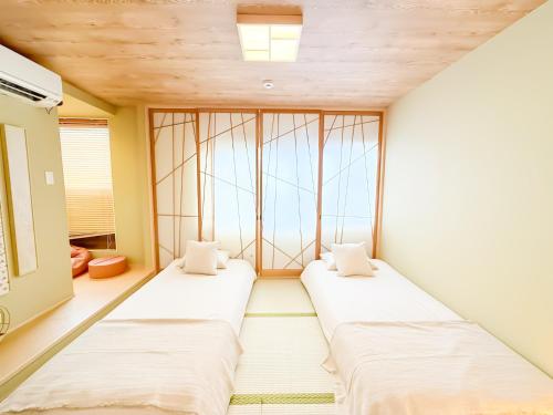two beds in a room with a window at Ōimazato-Japanese Garden Japanese Entire House with T a t ami Rooms for 8 & 5 Minutes Walk to Imazato &2 Baths 2 Toilets &Direct to Namba and Nipponbashi in Osaka