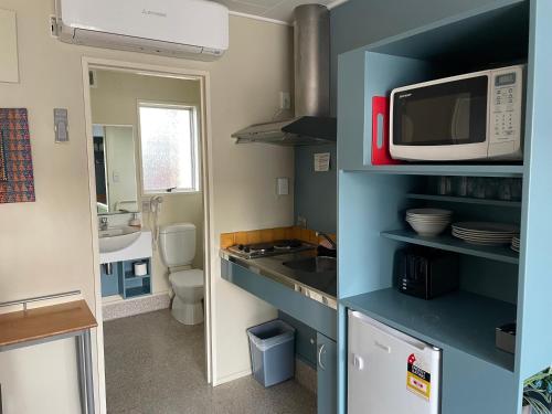 a small kitchen with a microwave and a sink at Bella Tuscany Motor Lodge in Napier