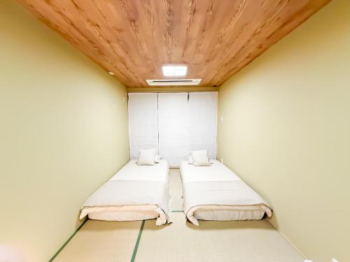 two beds in a room with a wooden ceiling at Ōimazato-Japanese Garden Japanese Entire House with T a t ami Rooms for 8 & 5 Minutes Walk to Imazato &2 Baths 2 Toilets &Direct to Namba and Nipponbashi in Osaka