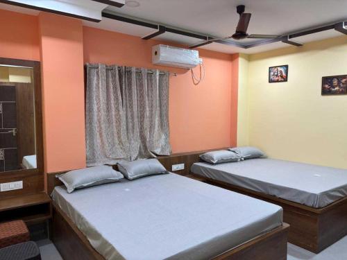 two beds in a room with orange walls at Collection O Asian Highway Near Agrasen Hospital Siliguri Formerly Ashiyana Homestay in Binnāguri