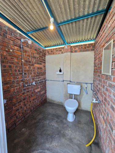 a bathroom with a toilet in a brick wall at bira pata glamping in Marang