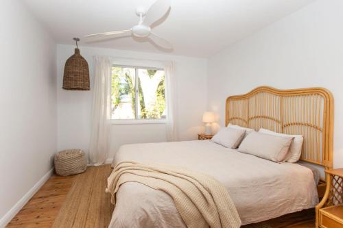 a white bedroom with a bed and a ceiling fan at Jimmys Beach House in Hawks Nest