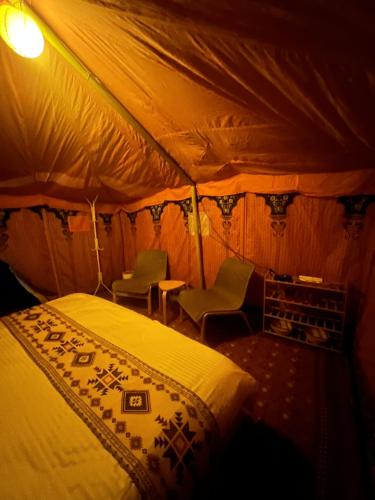 Al RakaにあるDesert Lumen Campのベッドルーム1室(ベッド1台、テント内の椅子付)
