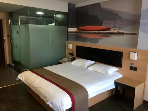 a bedroom with a bed and a painting on the wall at Thank Hotel Shandong Weifang North High-speed Railway Station in Weixian