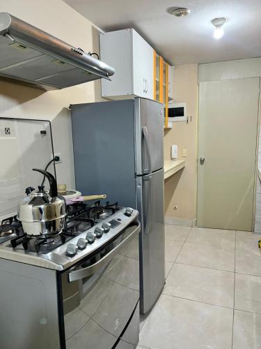 a kitchen with a stove and a stainless steel refrigerator at bonito departamento cerca al Aeropuerto Jorge Chávez in San Antonio