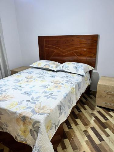 a bed with a wooden headboard in a bedroom at bonito departamento cerca al Aeropuerto Jorge Chávez in San Antonio