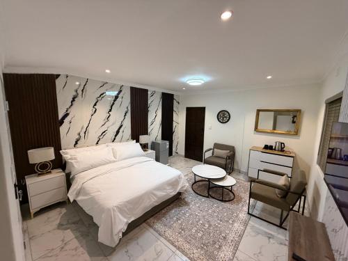 a bedroom with a bed and a desk and a chair at The Benjamin Guest House in Edenvale
