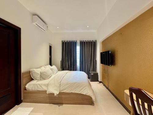 une chambre avec un lit avec des draps blancs et des oreillers dans l'établissement Amazing Merit Trung Son, à Hô-Chi-Minh-Ville
