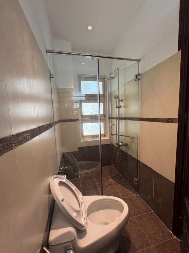 a bathroom with a toilet and a glass shower at Amazing Merit Trung Son in Ho Chi Minh City