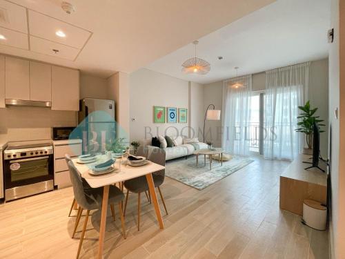 a kitchen and living room with a table and chairs at Bloomfields Relaxing 1Br in Yas Island Waters Ed in Yas Island