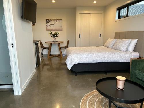 a bedroom with a bed and a table at Surf and Turf - Ocean Beach Getaway in Tuki Tuki