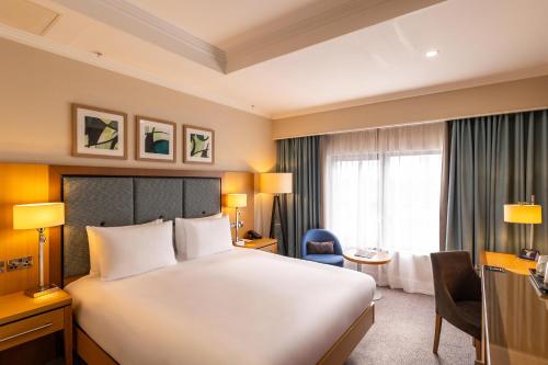 a hotel room with a large white bed and a window at DoubleTree by Hilton London Victoria in London