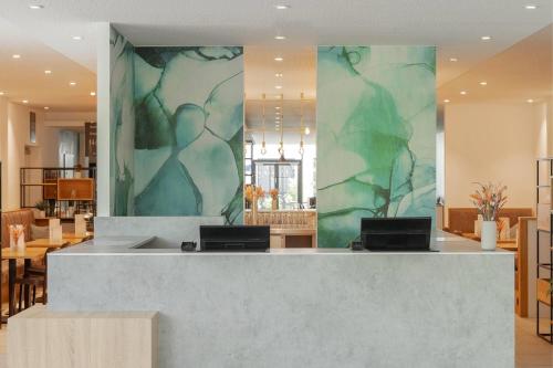 a lobby with a reception desk with a green wall at Wyndham Garden Munich Messe in Munich
