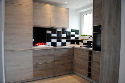 a kitchen with wooden cabinets and a black and white checkered wall at Apartament 1Maja in Koszalin