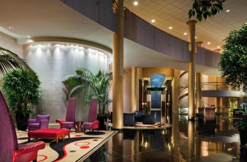 a lobby with purple and red chairs and plants at Hilton Washington Dulles Airport in Herndon