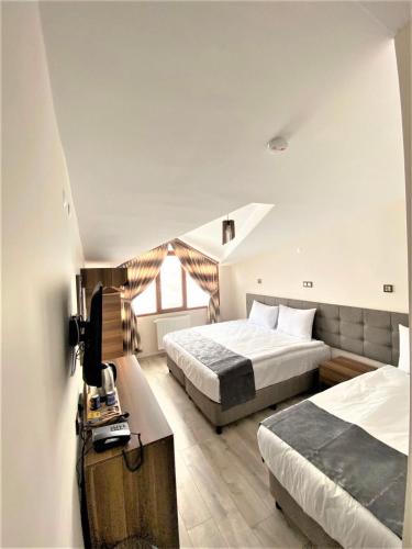 a bedroom with two beds and a television in it at Zümrüt Palas Otel in Erciyes