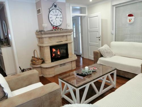 a living room with a fireplace and a clock on the wall at Vila Snjeguljica Blidinje 200 m od ski staze in Risovac
