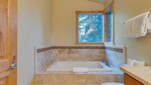 ein Bad mit einer Badewanne und einem Fenster in der Unterkunft Cozy Tahoe Retreat w Hot Tub Movie Room Forest Views 10th ave 2 by AvantStay in Tahoma