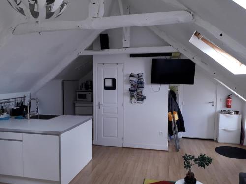 Una cocina con gabinetes blancos y un televisor en un ático. en Un nid douillet sous les toits, en Cancale