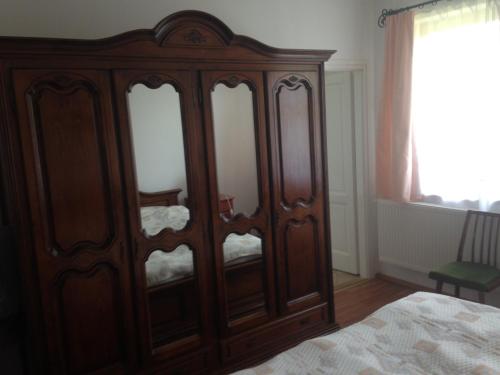 a wooden cabinet in a bedroom with a bed at Kölcsey Kúria Vendégház in Szatmárcseke