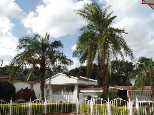 a white fence in front of a house with palm trees at Villa Leone Boutique Hotel in Nairobi