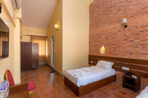 une chambre avec un lit et un mur de briques dans l'établissement Badreni Jungle Resort, Sauraha, à Bharatpur