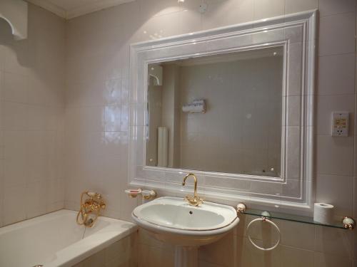 a bathroom with a sink and a tub and a mirror at Villa Leone Boutique Hotel in Nairobi