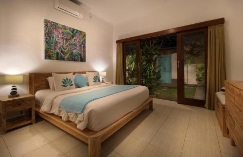 a bedroom with a large bed and a sliding glass door at Villa Lotus Flower Sanur in Sanur
