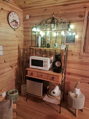 a microwave on a table in a room with a clock at Roulotte en bois in Fuveau