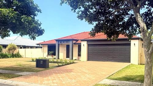 a house with a garage and a driveway at Fernando's Beach Hideaway in Banksia Beach