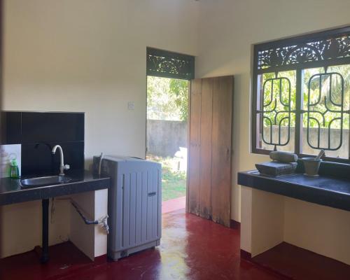 a kitchen with a sink and a refrigerator and windows at Viska Villa 2 Bedroom Home 5 min to Hiriketiya in Nilwella