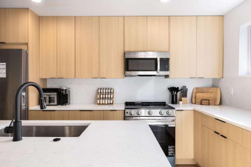 une cuisine avec des armoires en bois et des appareils en acier inoxydable dans l'établissement 2025 Modern 2BR Home Near Sea-Tac & Boeing, à Seattle