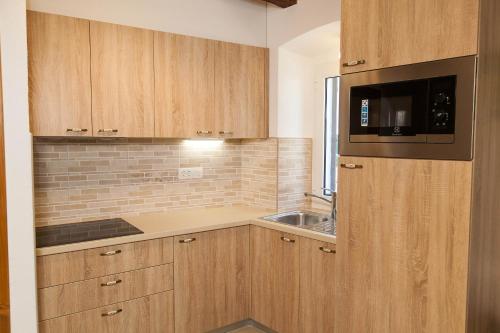 a kitchen with wooden cabinets and a microwave at Holiday Home NiKa in Omišalj