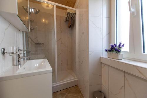 a white bathroom with a shower and a sink at Holiday Home NiKa in Omišalj