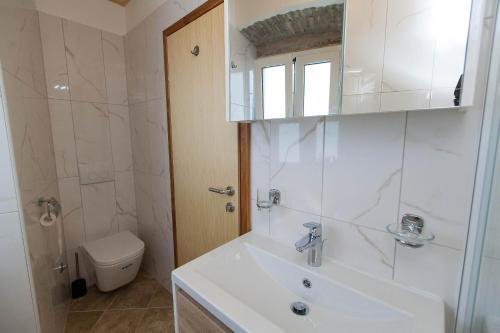 a white bathroom with a sink and a toilet at Holiday Home NiKa in Omišalj