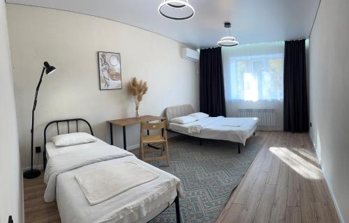 ein Schlafzimmer mit zwei Betten und einem Tisch und einem Fenster in der Unterkunft Новая квартира со всеми условиями Сити центре in Oral