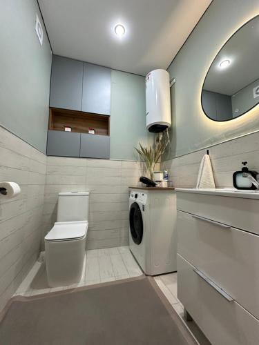 ein Badezimmer mit Waschmaschine und Waschbecken in der Unterkunft Новая квартира со всеми условиями Сити центре in Oral