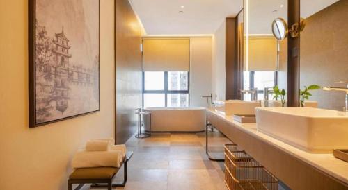 a bathroom with three sinks and a bath tub at Wanda JIN Baise in Qitang