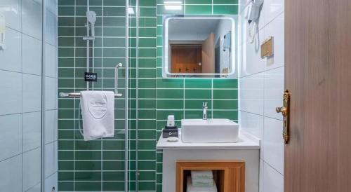済寧市にあるGreenTree Inn Jining Jianshe Road Hotelの緑のタイル張りのバスルーム(シンク、鏡付)
