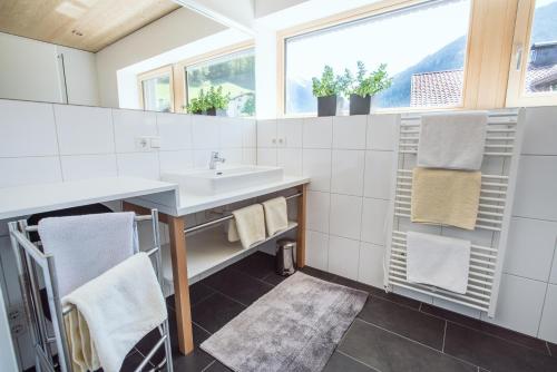 a white bathroom with a sink and towels at AlpenApart Montafon - Appartement Sennerei in Schruns-Tschagguns