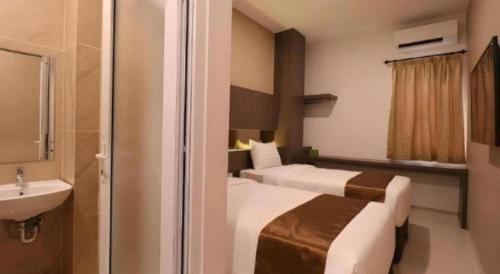 a hotel room with two beds and a sink at NIVIA HOTEL in Pulauberayan Dadap