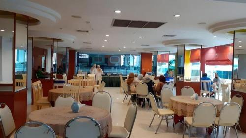 Ban Si ThanにあるPratunam Hotelのテーブルと椅子、座り人が座るレストランです。