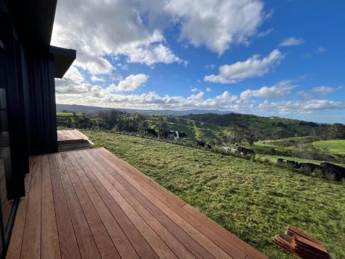 a wooden deck with a view of a green field at Golden Ridge Retreat in Otorohanga